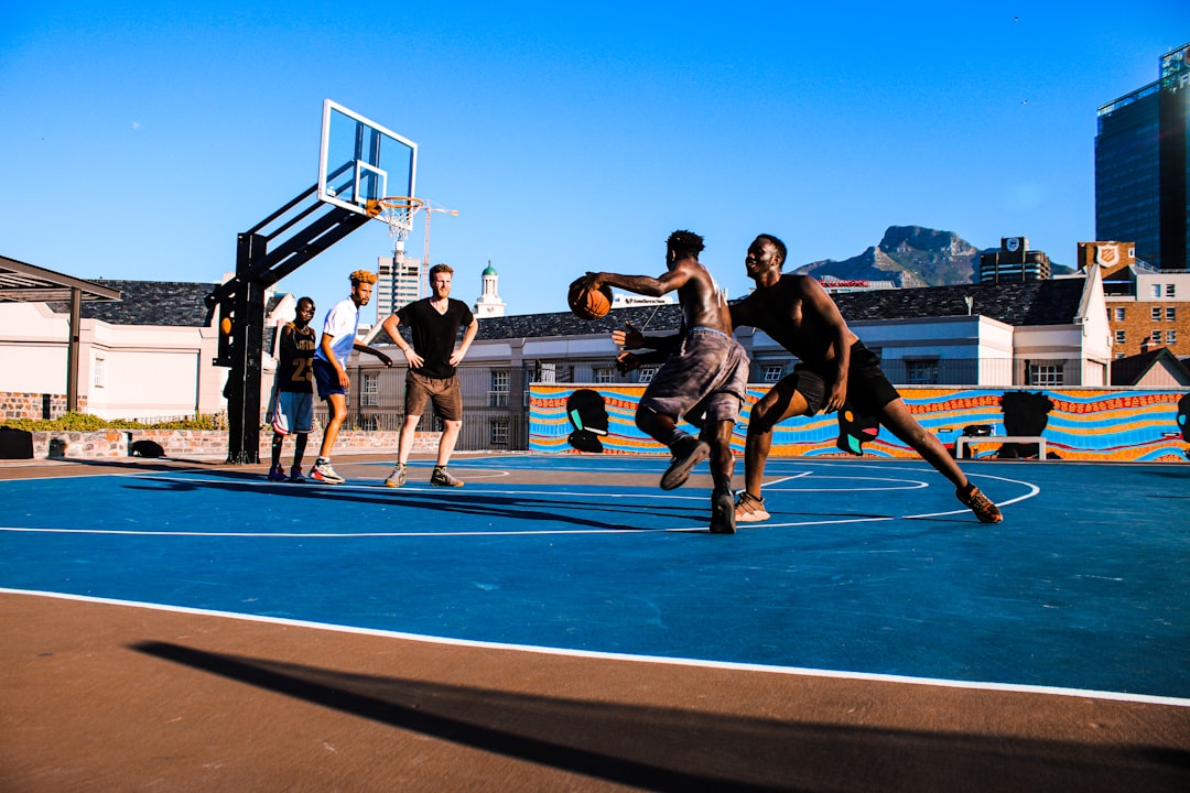 A dynamic basketball court scene showing multiple players demonstrating fundamental techniques including dribbling, shooting form, and defensive stance, with subtle overlay of court lines and key rule